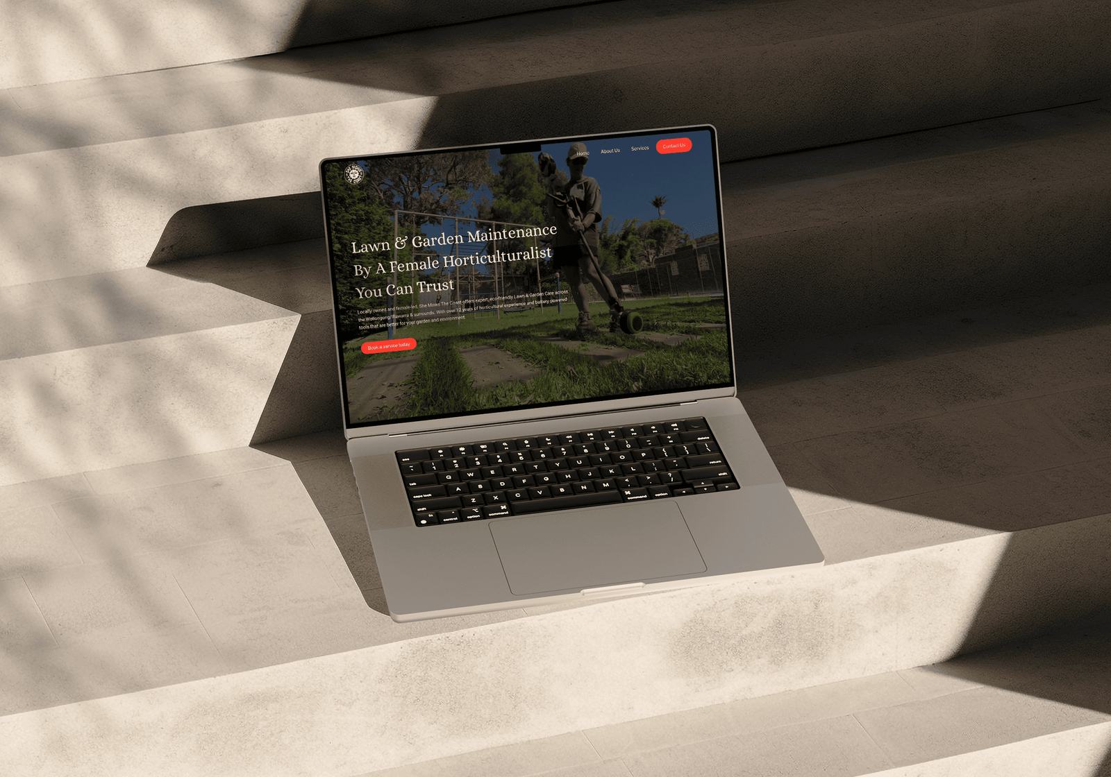 She Mows The Coast Home page on laptop mockup