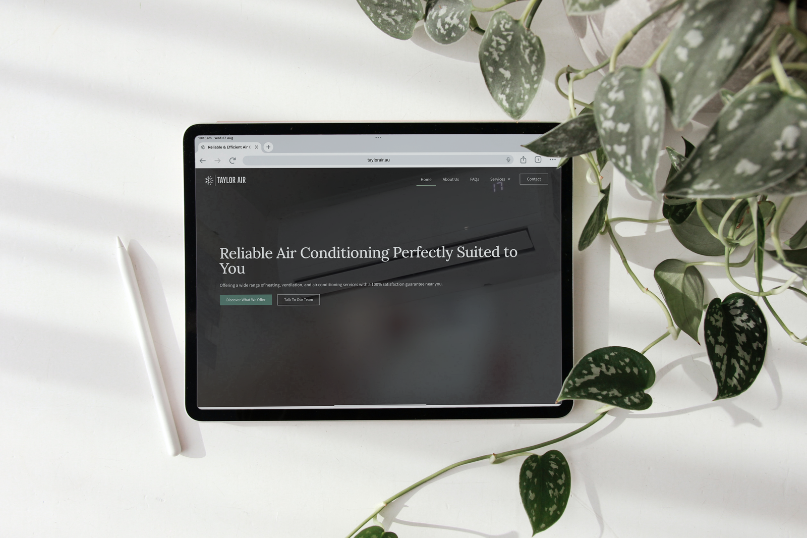 taylor air website on ipad with apple pencil and with plant decorations in top right hand corner